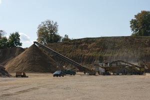 gravel pit with yellow machine moving gravel and rocks in the pit
