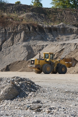 gravel pit with yellow machine driving in the pit