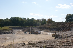 gravel pit with yellow machine moving gravel and rocks in the pit